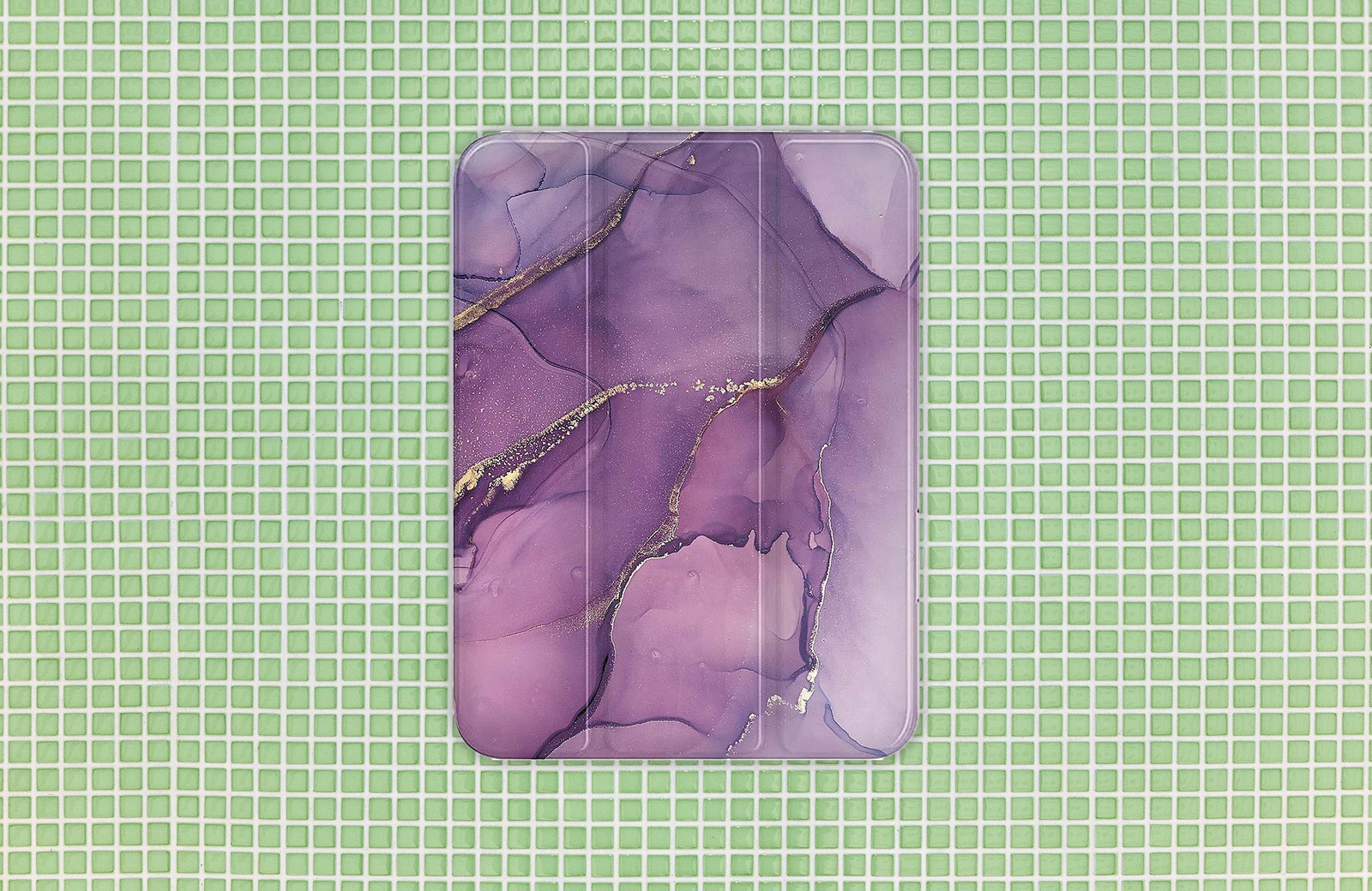 Purple and gold marble patterned tablet case. Background Green tiles