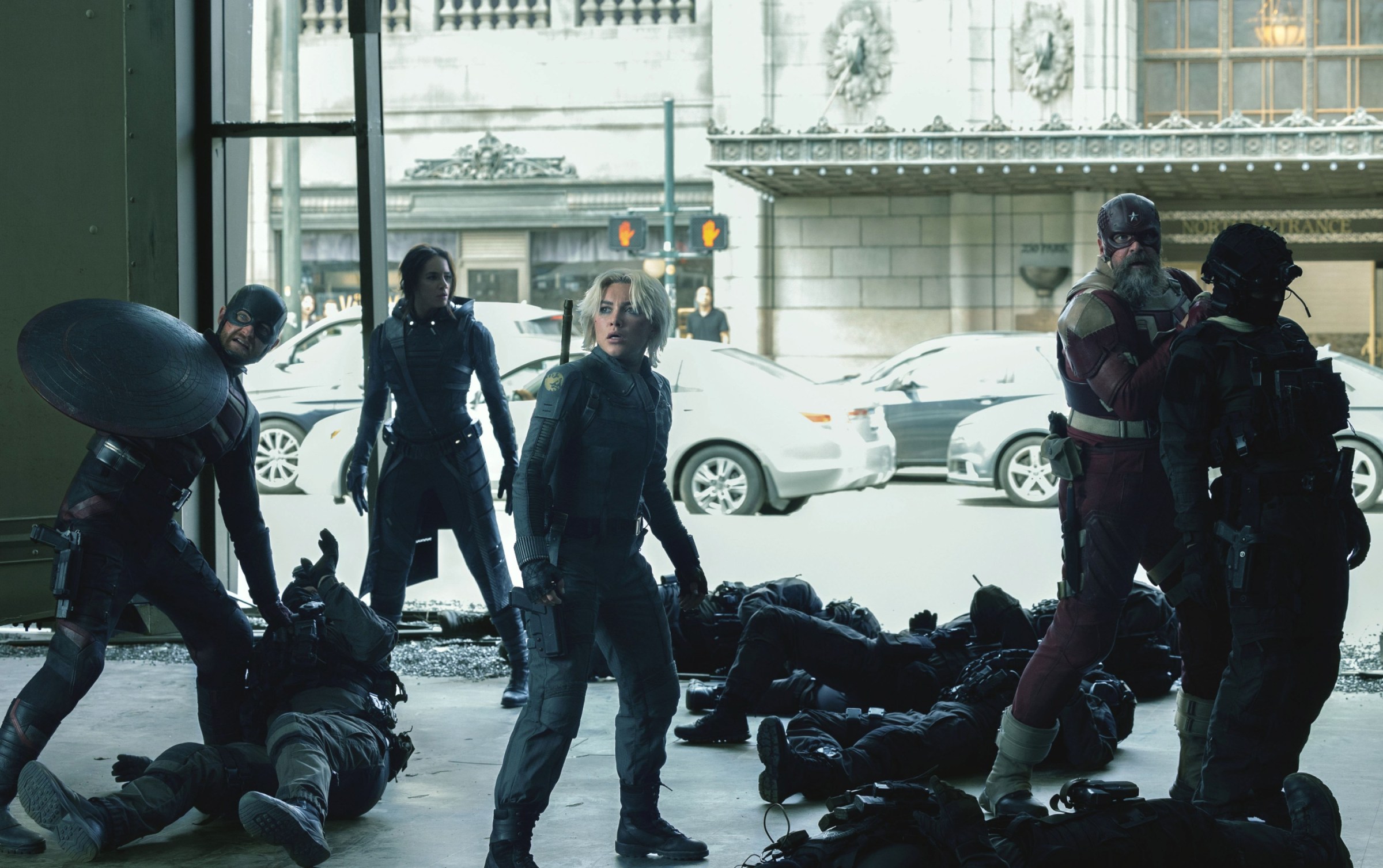 The Thunderbolts — Wyatt Russell as John Walker, Hannah John-Kamen as Ghost, Florence Pugh as Yelena Belova, David Harbour as Red Guardian — stand together, surrounded by a group of armored men they’ve just knocked out, in Thunderbolts*.