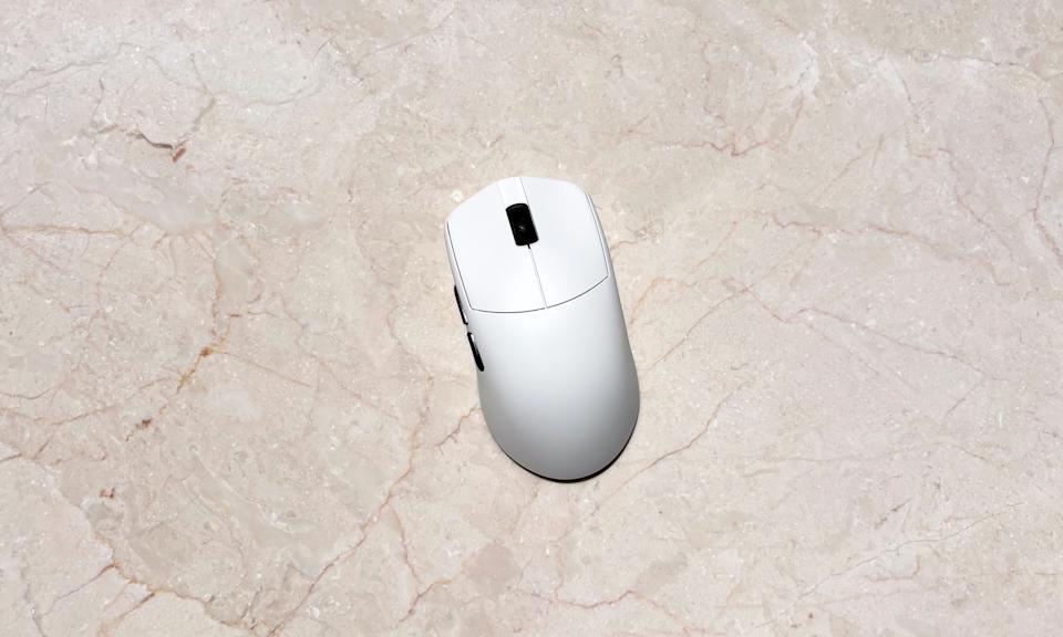 A white gaming mouse rests on a marble table.