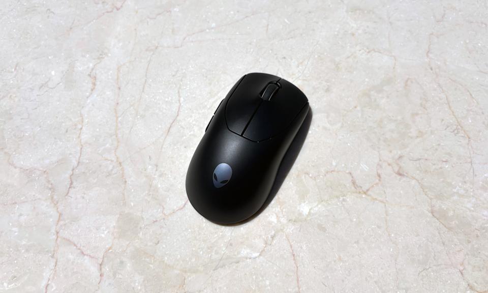A black gaming mouse rests on a white marble table.