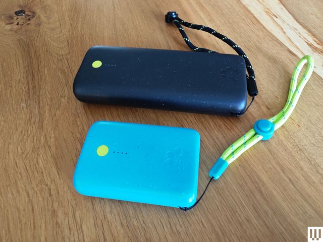 Small rounded rectangular bright blue device beside a black rectangular device, both with strap handles.