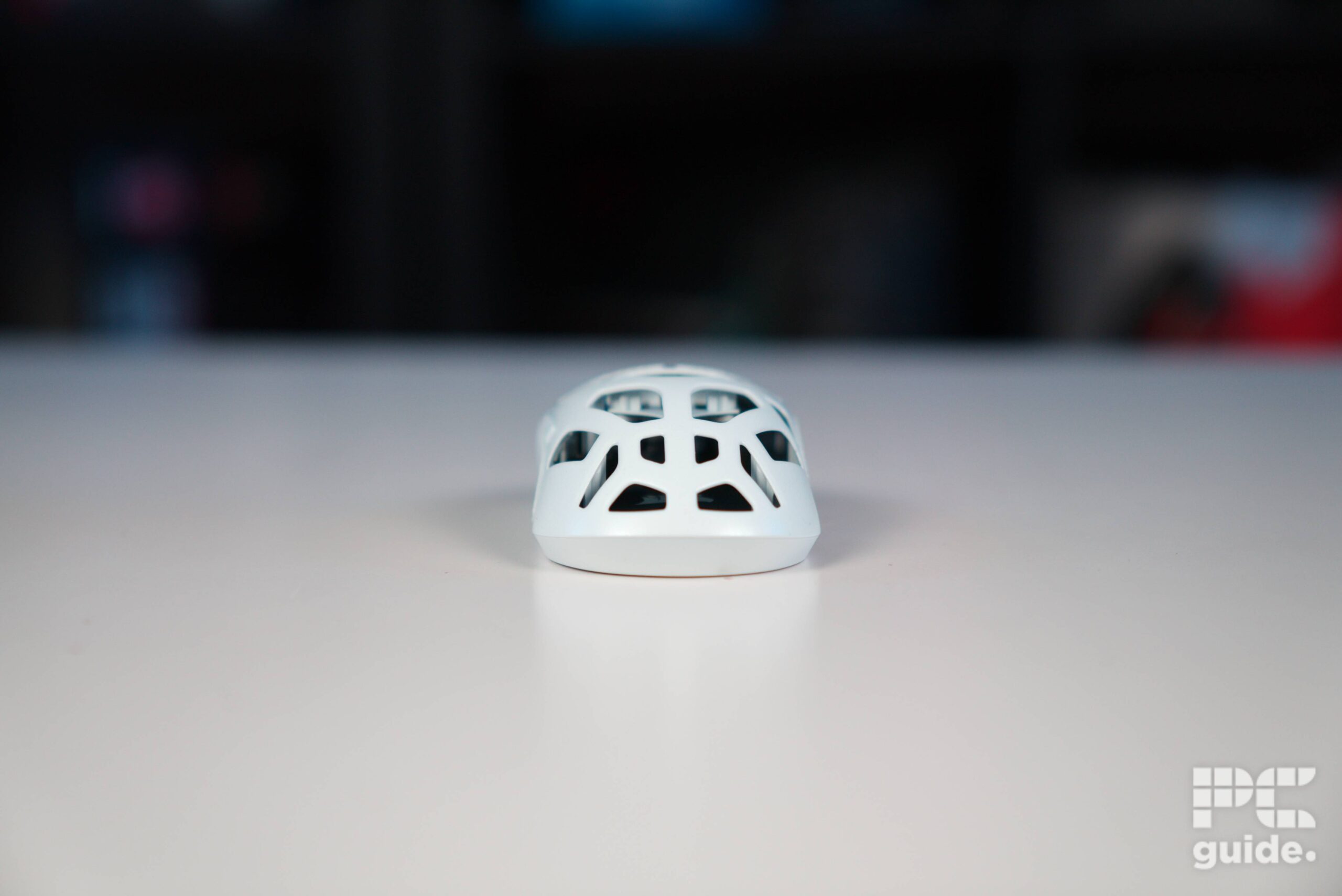A shot of the back of the white Corsair Sabre v2 PRO Wireless MG on a white table, it has holes over the body.
