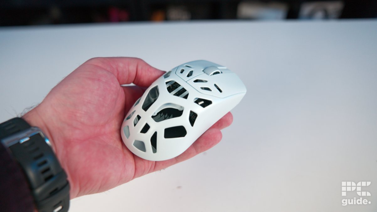 The white Corsair Sabre v2 PRO Wireless MG being held in hand showing the holes in the body.