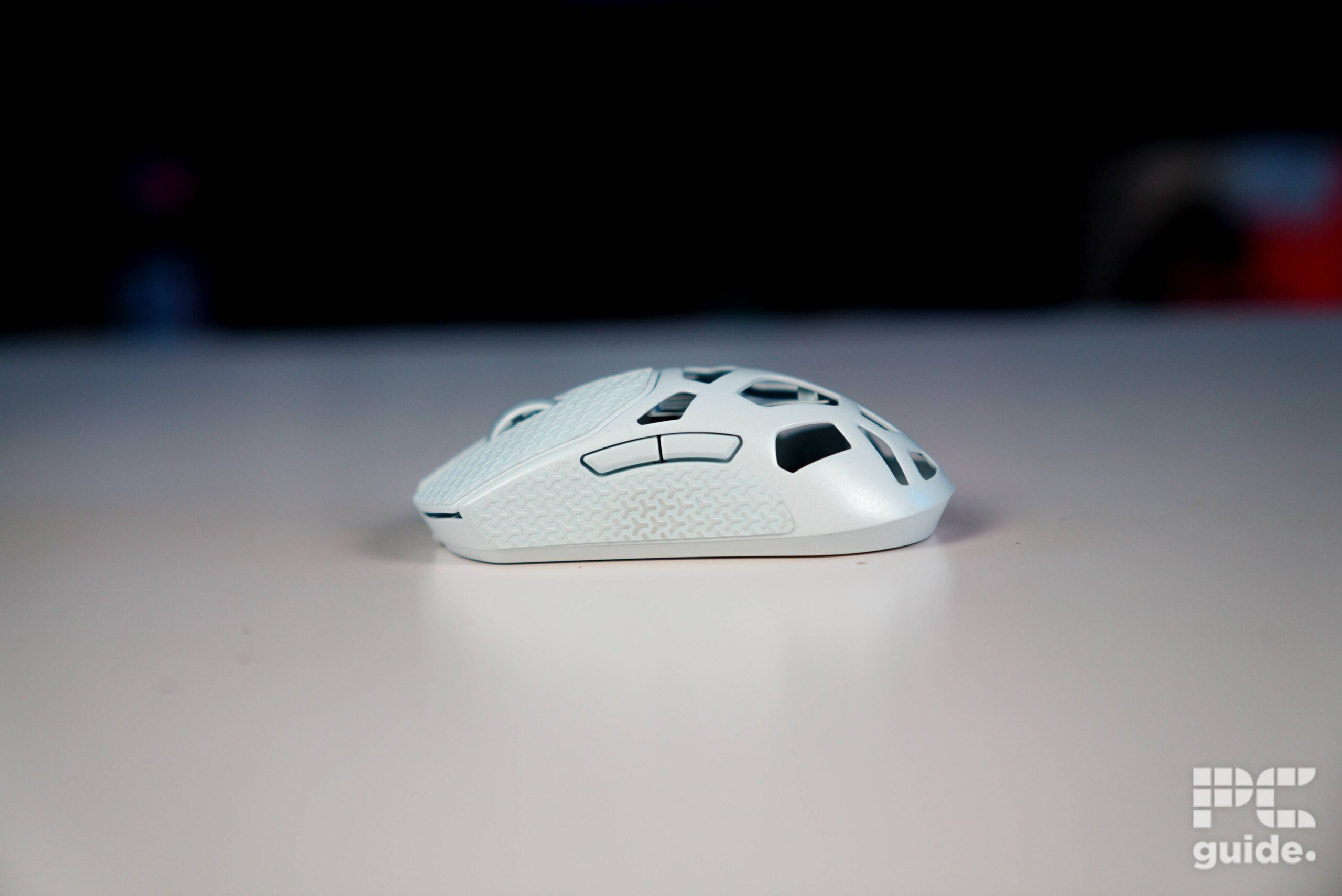 The left side of the white Corsair Sabre v2 PRO Wireless MG on a table. Showing two buttons at the top.